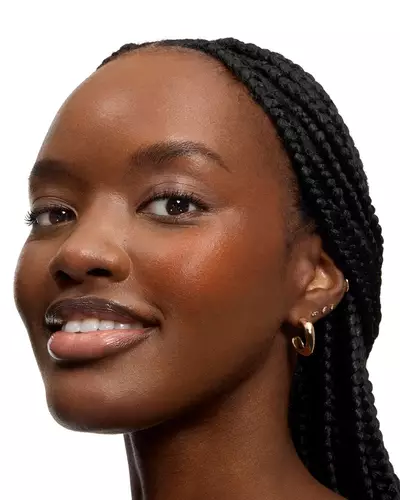 Smiling woman with long braids and glossy lips.