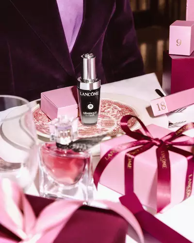 Lancome beauty products and pink gift boxes arranged on a festive dining table.