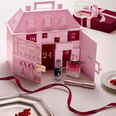 An open pink Lancome townhouse advent calendar displayed with beauty products and a red ribbon.