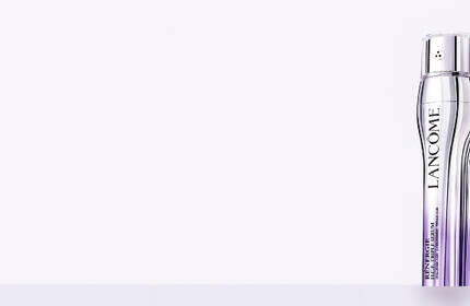 A promotional image featuring two Lancome skincare products against a soft purple background.