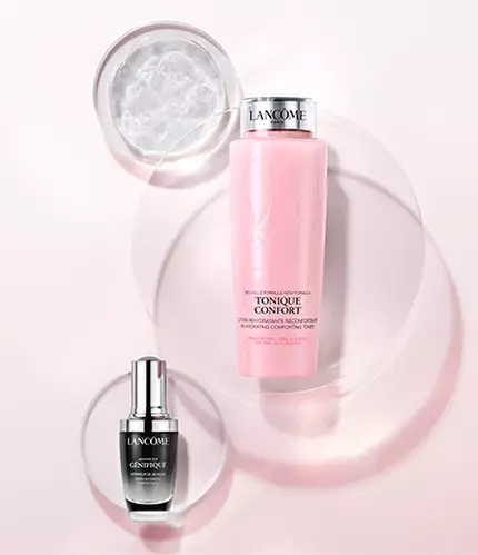 A minimalist display featuring two skincare products on a soft pink background: a black serum bottle and a pink lotion bottle, surrounded by circular, translucent shapes.