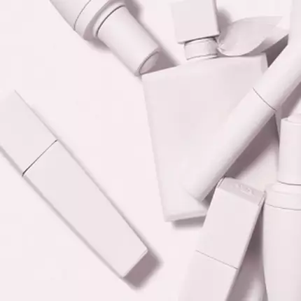 A collection of minimalist white cosmetic containers arranged artistically against a light background.