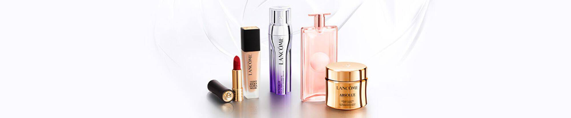 A collection of Lancome beauty products, including a lipstick, serum, perfume, and skincare cream, displayed elegantly against a light background.