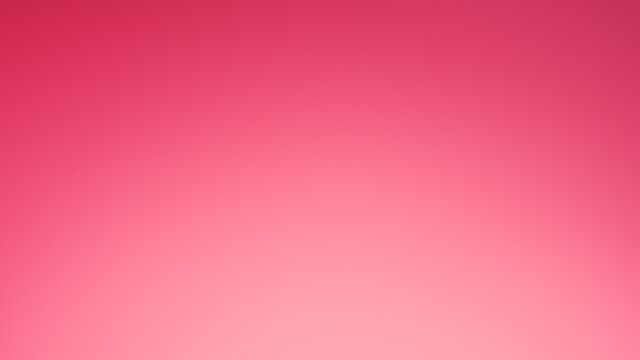 A vibrant pink background featuring a luxurious red gift box with a satin ribbon, showcasing the Lancome Paris logo on the top.