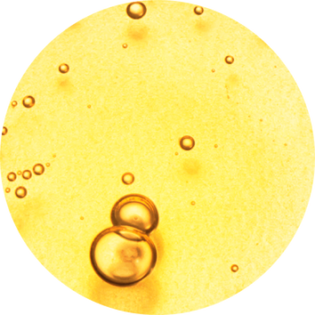 Close-up of amber-colored liquid with small, floating air bubbles creating a textured surface.