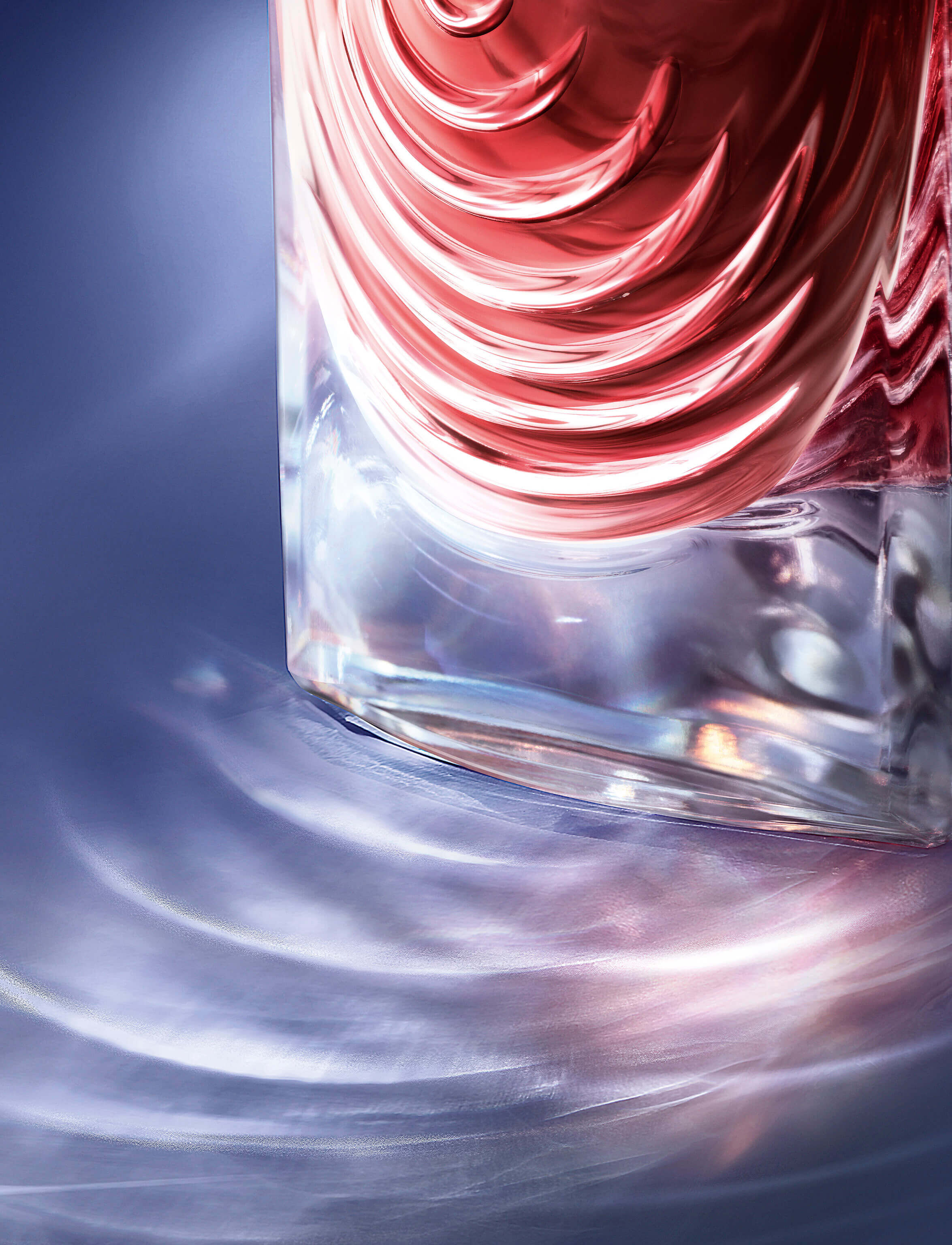A close-up of a glass bottle with a swirling design, reflecting light on a smooth surface, creating colorful patterns in the background.