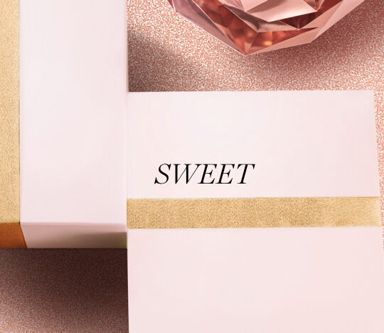 Two elegantly wrapped gift boxes with a gold ribbon on a sparkling background, featuring the word "SWEET" prominently displayed.