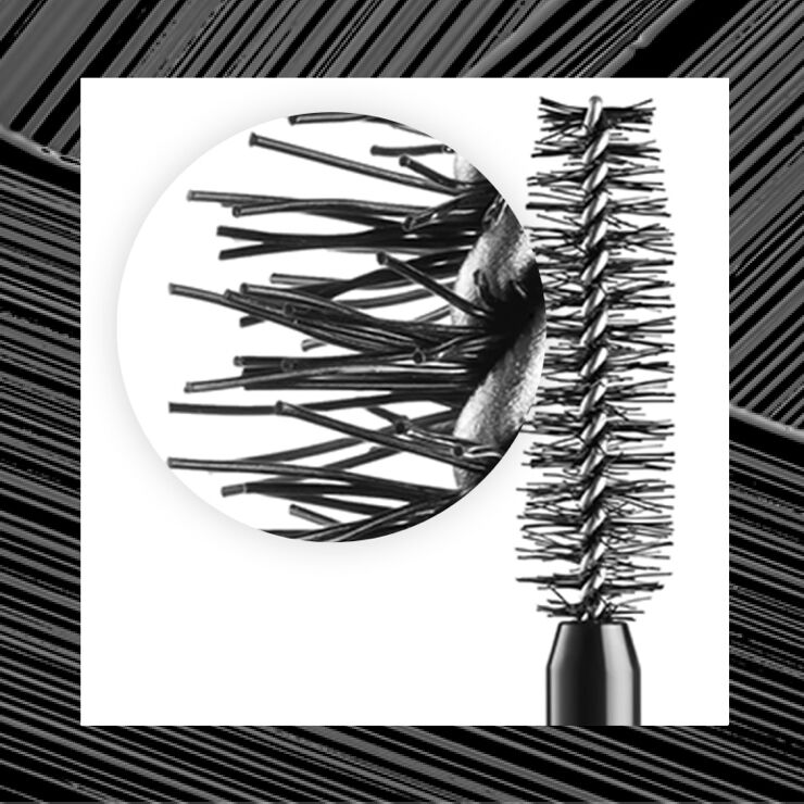 A close-up of a mascara brush showing its bristles, with a black and white background pattern.