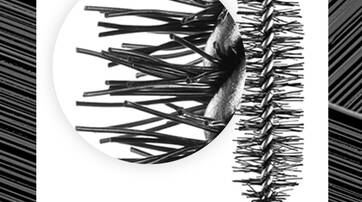 A close-up of a mascara brush showing its bristles, with a black and white background pattern.