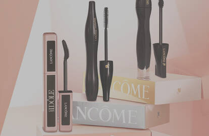 A collection of Lancome mascaras displayed on pastel-colored boxes, featuring various styles and designs of mascara tubes.
