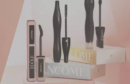 A collection of Lancome mascaras displayed on pastel-colored boxes, featuring various styles and designs of mascara tubes.