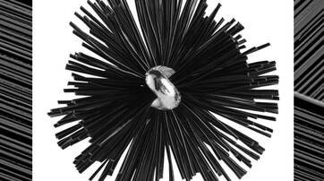 A close-up of a black spherical object made of numerous thin, spiky strands, with a shiny central core, set against a contrasting background.