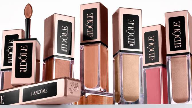 A collection of Lancome Idole Tint lip products displayed with elegant packaging in varying shades of nude and pink.