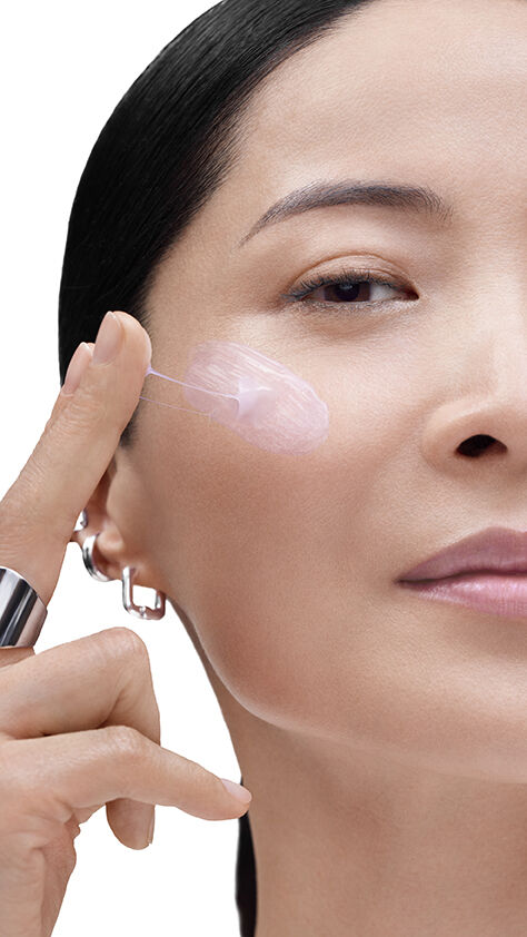 Model applying Lancome product to her cheek, highlighting radiant, plump skin.