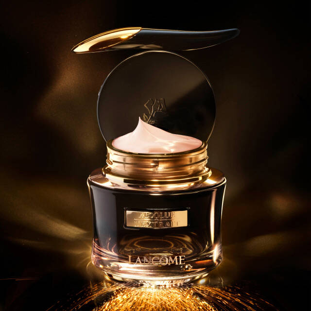 A luxurious cream jar with a sleek gold lid, illuminated against a dark background, showcasing a soft, creamy texture.