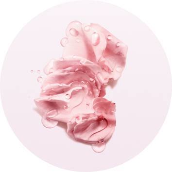 Soft pink cream smeared artistically with water droplets on a light background, evoking a fresh and soothing aesthetic.