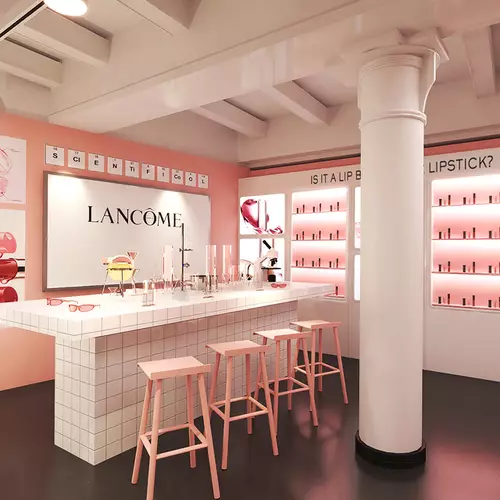 A bright and modern interior of a cosmetics store featuring pink walls, a white counter with makeup displays, and a bold blackboard. The space is well-lit and inviting, showcasing various beauty products.