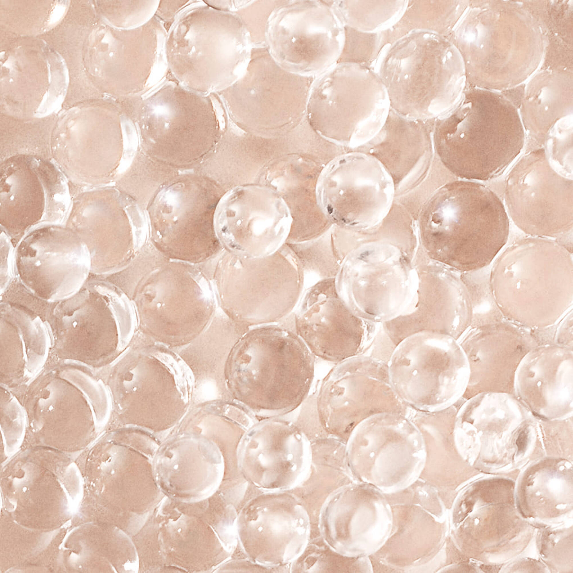 A close-up image of numerous small, transparent gel beads scattered on a smooth surface.