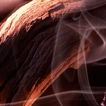Close-up of textured wood with soft, swirling smoke flowing around it, creating a warm and atmospheric ambiance.