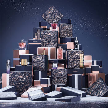 An elegantly arranged display of Lancome gift boxes and cosmetic products, set against a snowy background.