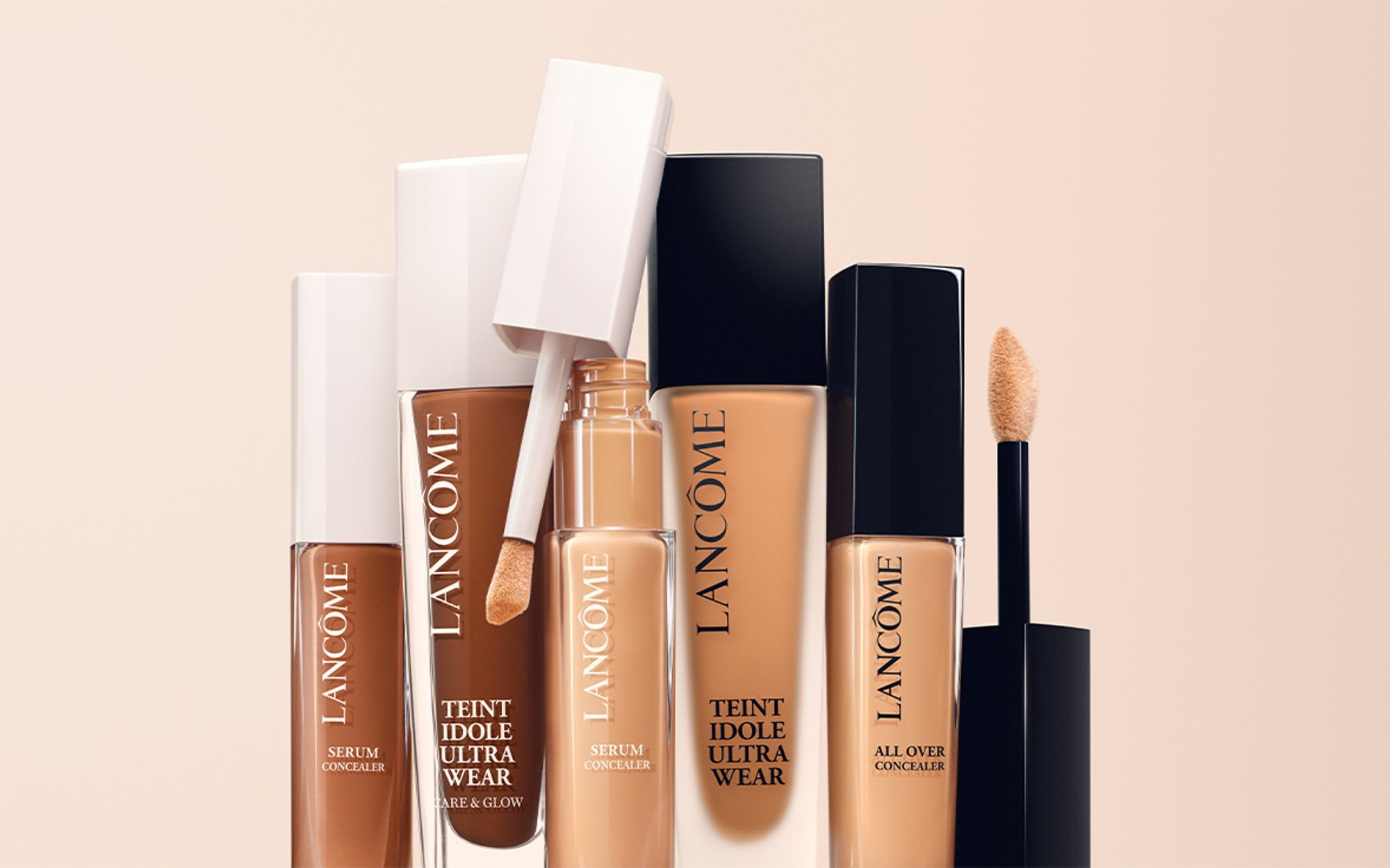 A collection of Lancome foundation and concealer products arranged vertically, featuring various shades and applicators against a neutral background.