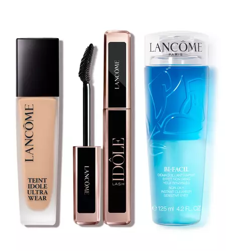 A collection of three Lancome beauty products: a foundation bottle labeled "Teint Idole Ultra Wear," a mascara tube labeled "Idole Lash," and a blue makeup remover labeled "Bi-Facil."