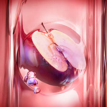 Close-up of a sliced apple immersed in a glossy, pink liquid with bubbles, showcasing vibrant textures and colors.