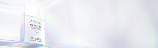 A sleek, modern bottle of Lancome’s "UV Expert Super Aqua" sunscreen with a reflective, iridescent background.
