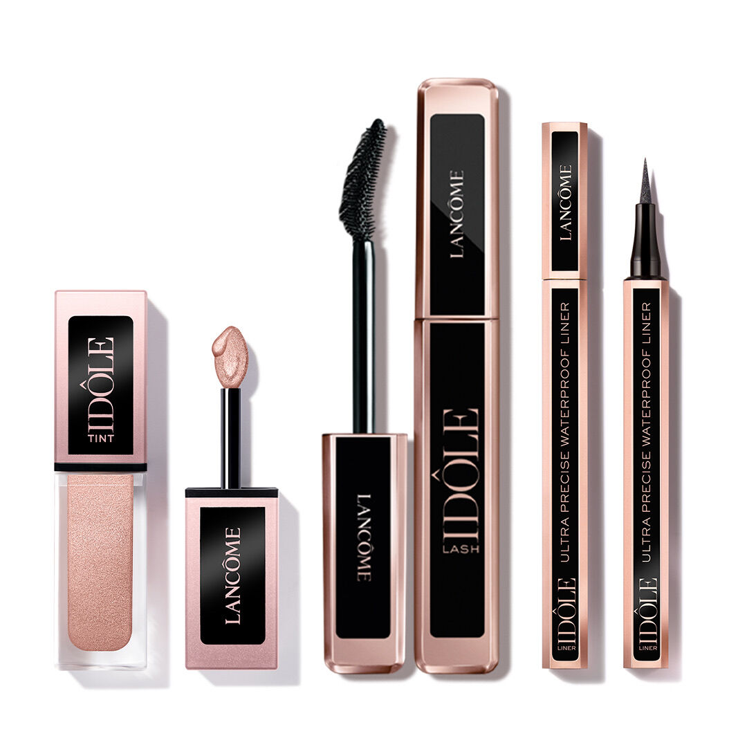 A variety of Lancome makeup products including a lip tint, a mascara, and a waterproof eyeliner, all featuring elegant packaging with a rose gold color scheme.