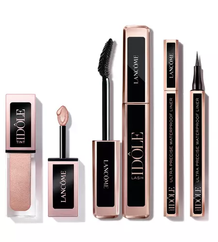A variety of Lancome makeup products including a lip tint, a mascara, and a waterproof eyeliner, all featuring elegant packaging with a rose gold color scheme.