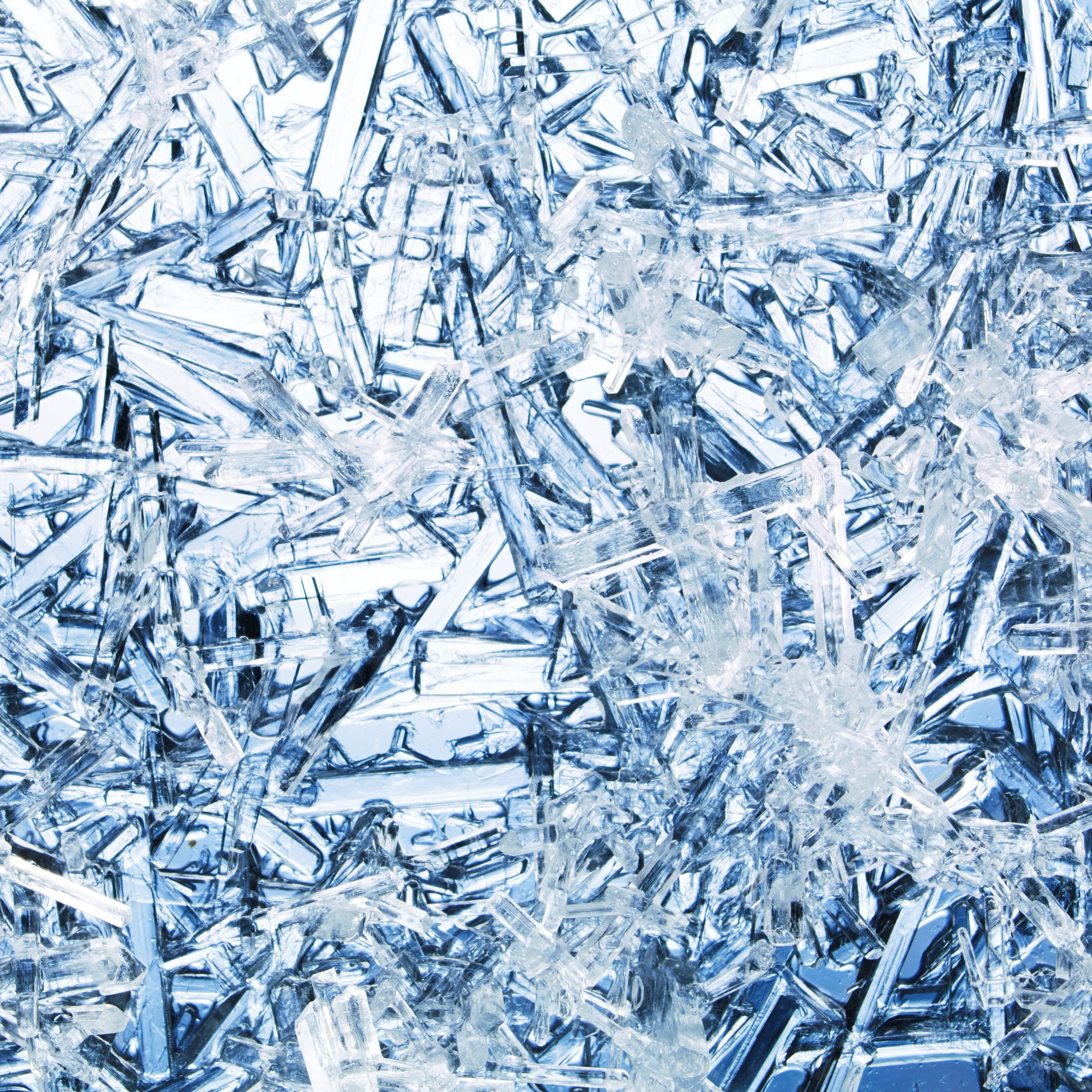 Close-up of intricate ice crystals glistening in shades of blue, creating a sparkling and textured surface.
