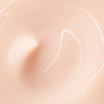 Close-up of creamy, beige makeup swatch with smooth, swirling patterns on a soft, neutral background.
