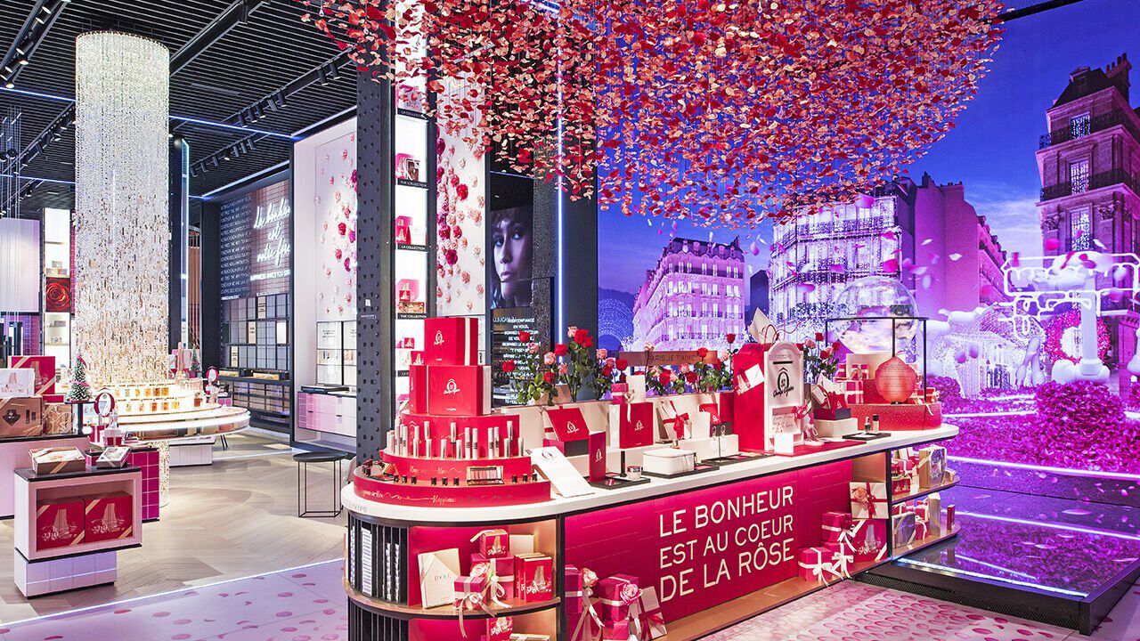 A vibrant retail store filled with pink and red rose-themed decorations, featuring beautifully arranged displays of products. The walls are adorned with colorful visuals, creating a festive atmosphere.