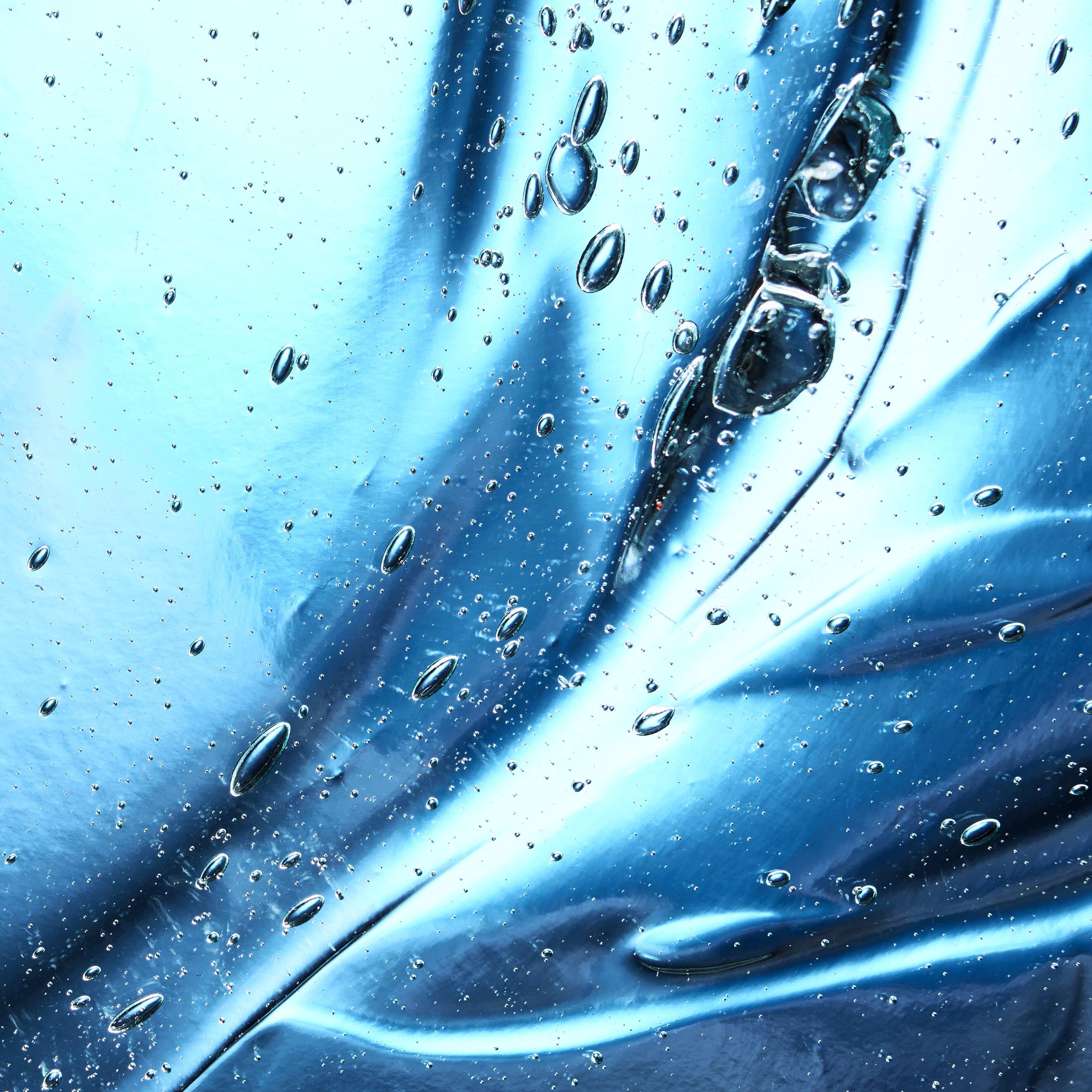 Close-up of shimmering blue liquid with bubbles and ripples creating a dynamic, fluid texture.