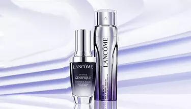 Two Lancome serums, Advanced Genifique and Renergie H.C.F. Triple Serum, are showcased against a light purple background with diagonal shadow stripes.