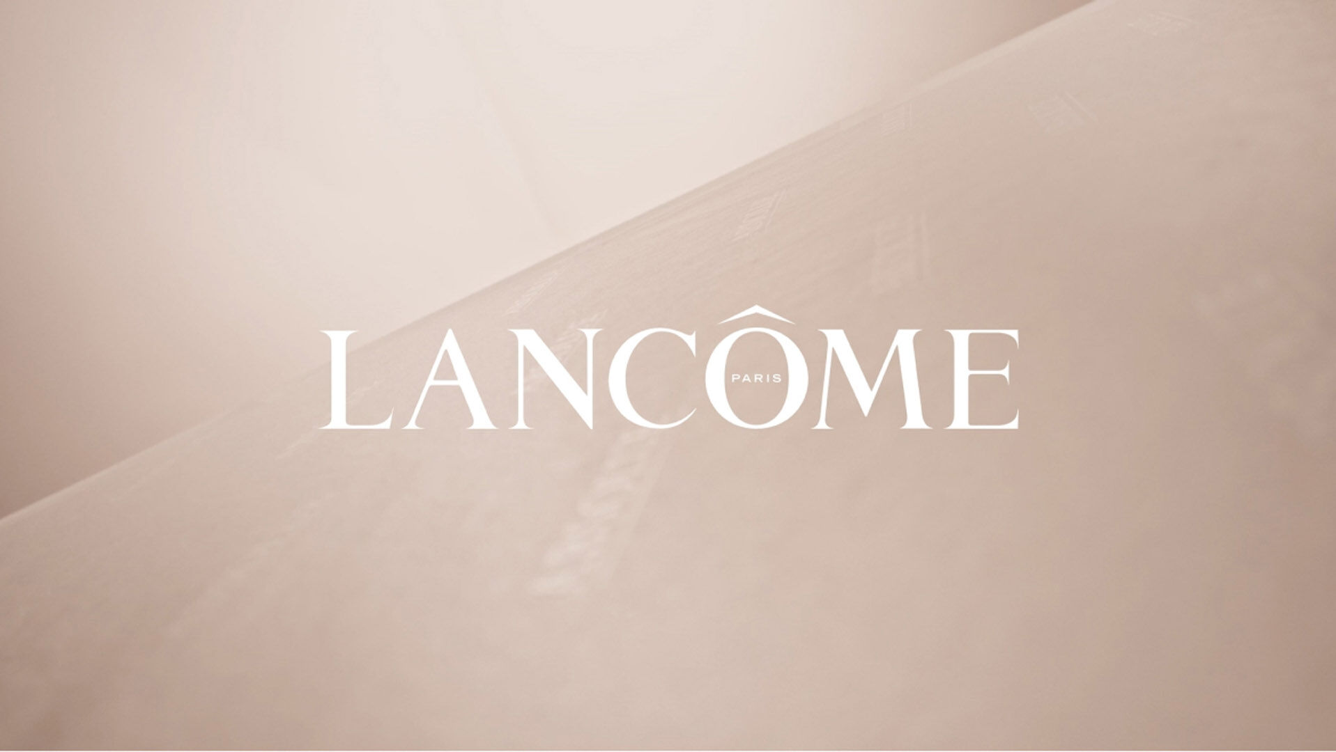 Elegant close-up of the Lancôme logo, set against a soft, beige background, conveying luxury and sophistication.